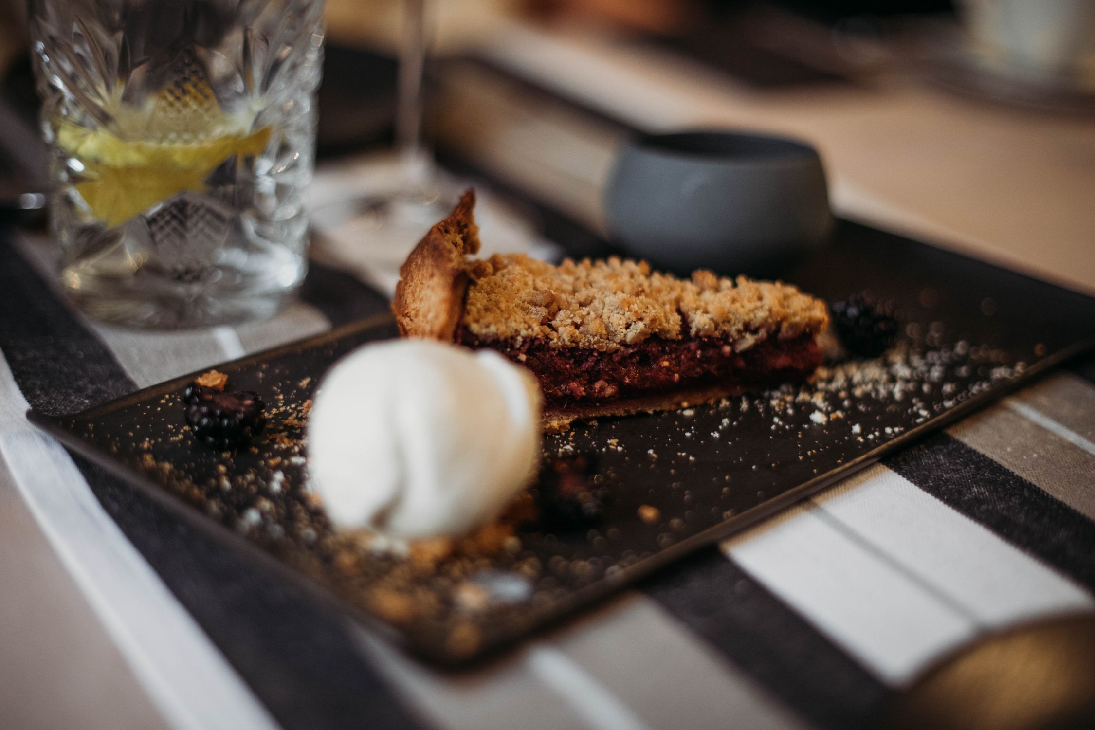 A slice of blackberry crumble pie served with a scoop of ice cream