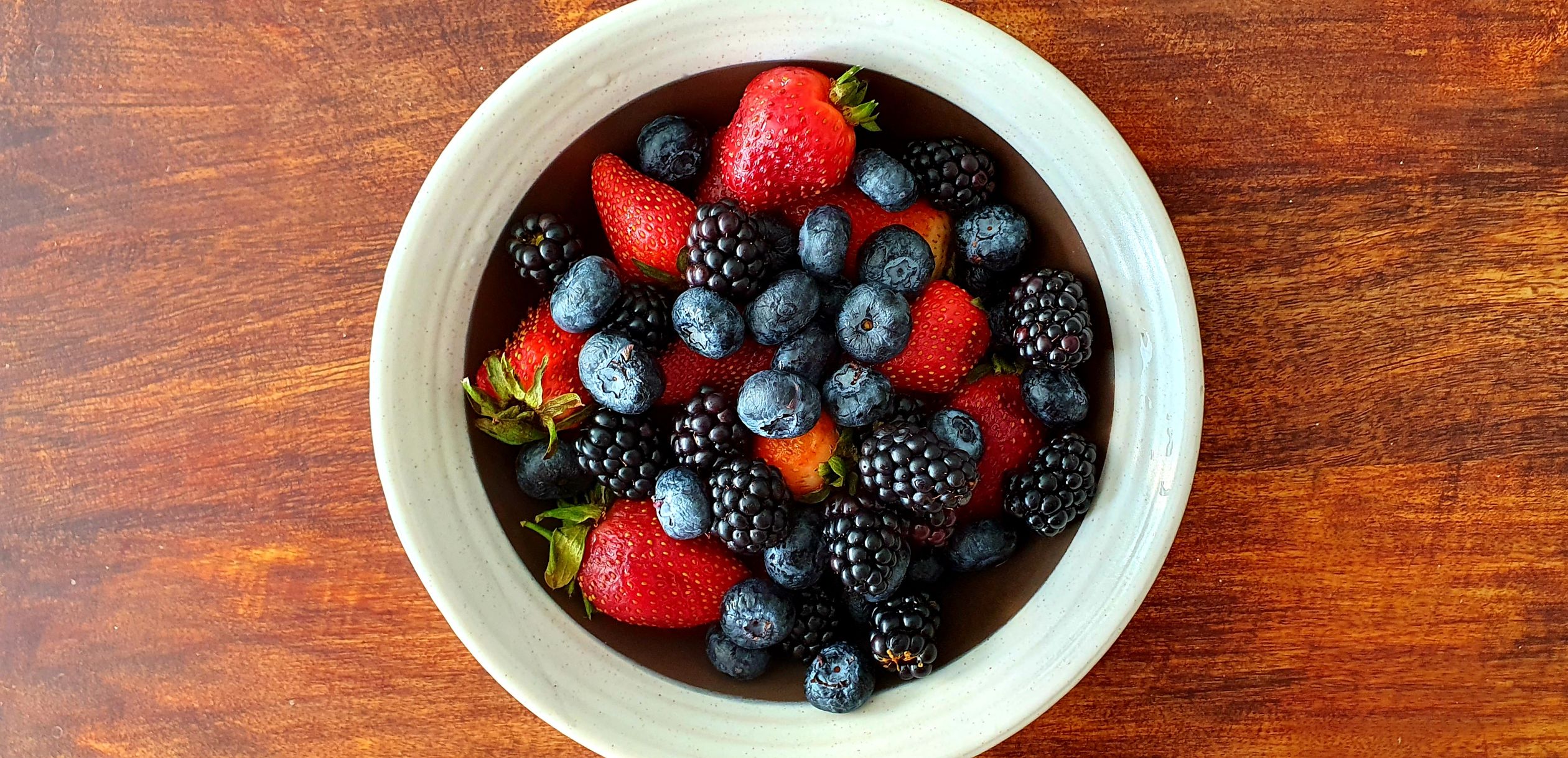 Bowl of fresh mixed berries on a wooden table - British Berries Guide